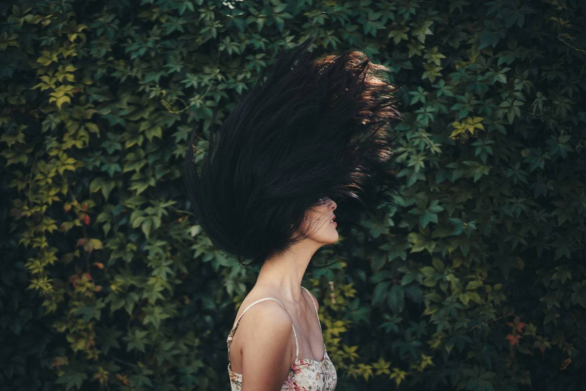 A woman holding velvet hair rollers with volumized curls styled using them.