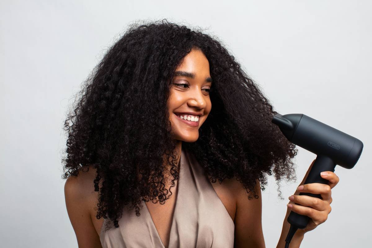 Woman applying leave-in conditioner before inserting hair rollers