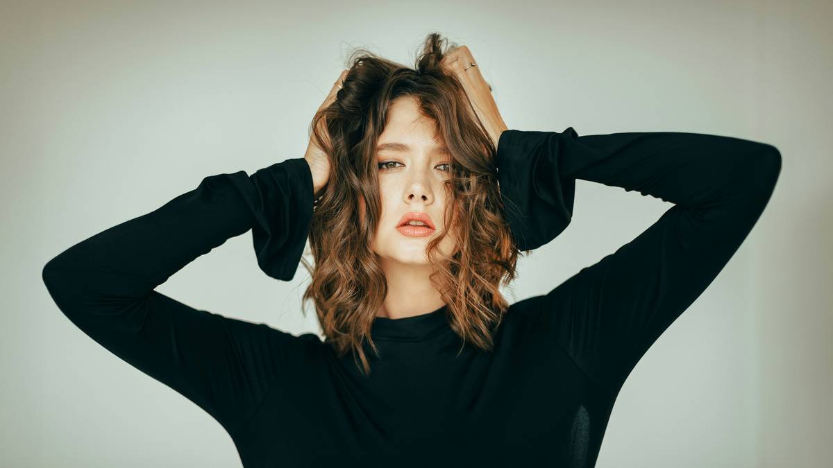 A woman applying hair rollers on damp hair for a natural look