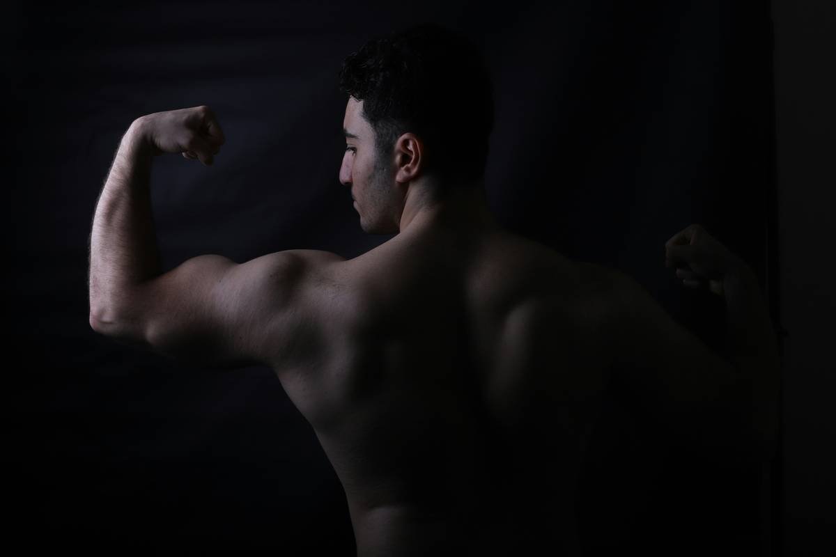A bodybuilder flexes his biceps for the camera.