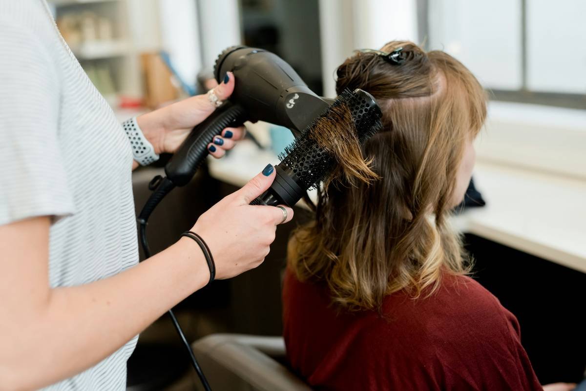 Stylist using a heat-resistant curling iron holder on a clutter-free vanity