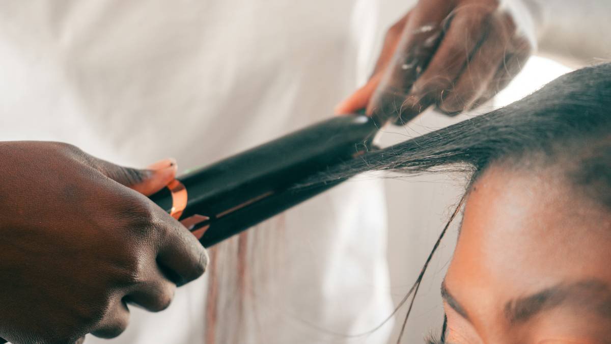 woman using curling iron brush to create defined curls on shoulder-length hair