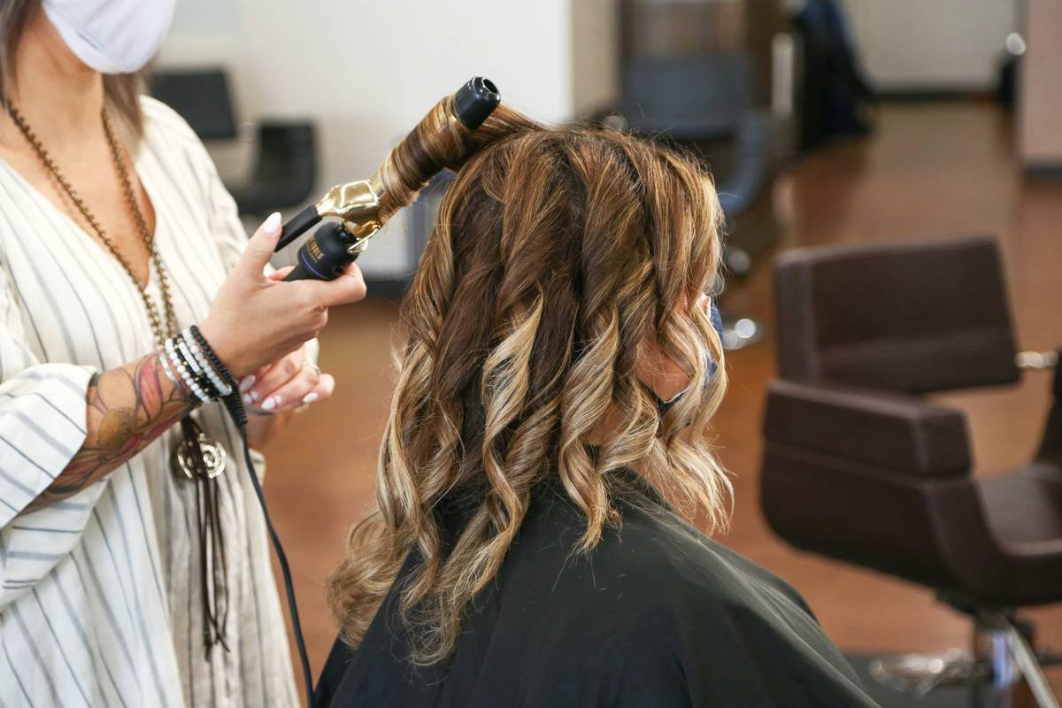 close-up of curling iron brush creating soft waves on fine hair with heat protectant applied